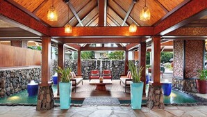 A covered outdoor seating area with stone walls, wooden beams, and hanging lights.