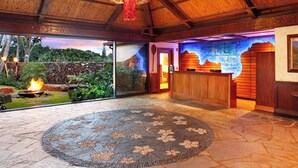 A hotel lobby with a stone floor, a reception desk, and a glass wall offering a view of a landscaped garden.