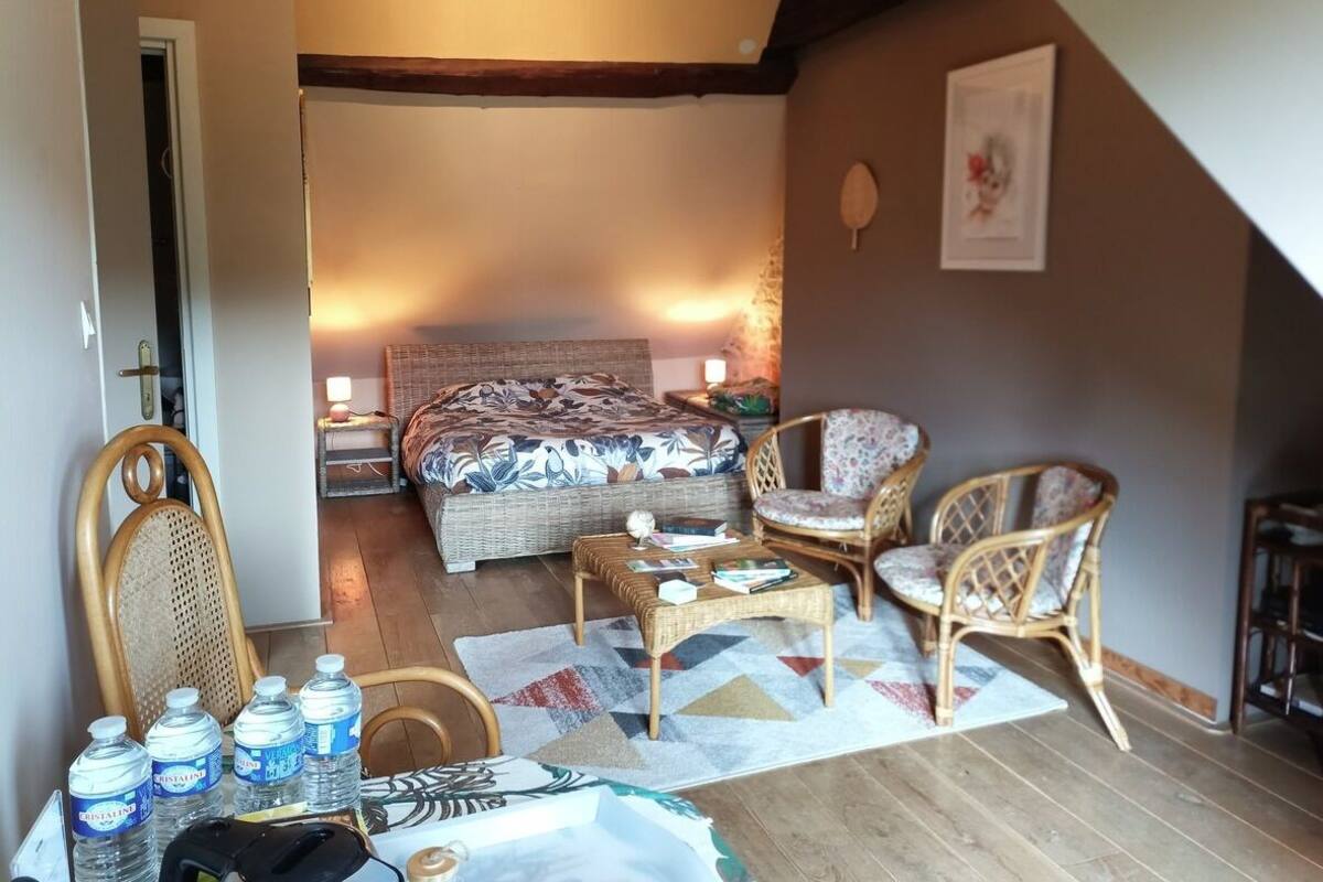 A cozy bedroom with a bed, wicker furniture, a coffee table, and water bottles on a table.