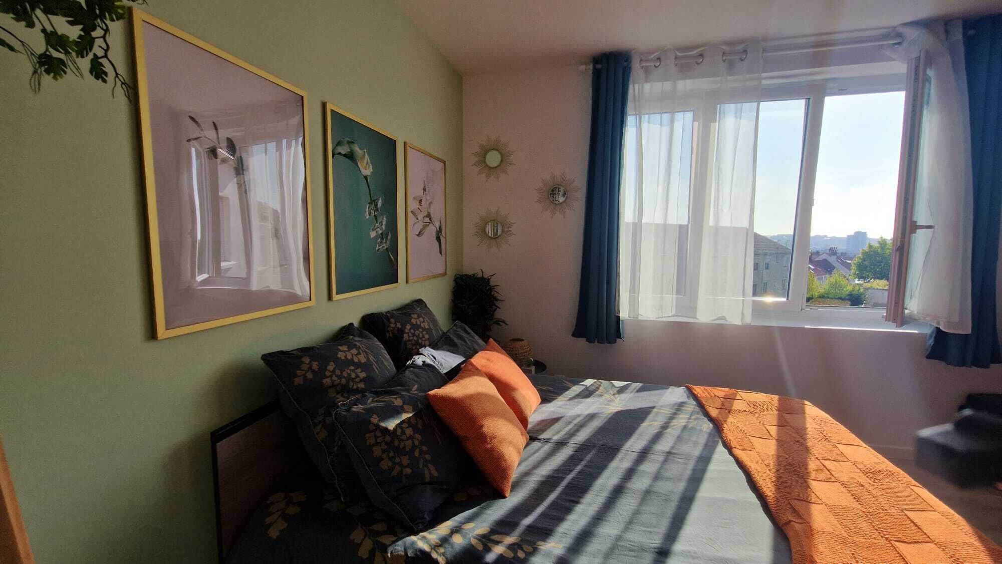 Un dormitorio con cama, ventana con cortinas y adornos en la pared.