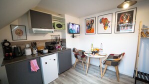 A compact kitchen with a microwave, toaster, and coffee maker. There is a small refrigerator, a sink, and a dining area with two chairs and a table. - Residence Kelys (Boulogne-sur-Mer)