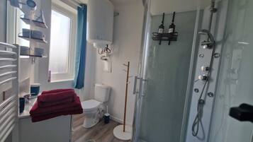 A bathroom with a toilet, a shower, and a sink.