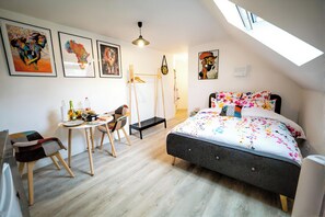 Une chambre à coucher comprenant un lit, un bureau, une chaise et des œuvres d’art accrochées aux murs.