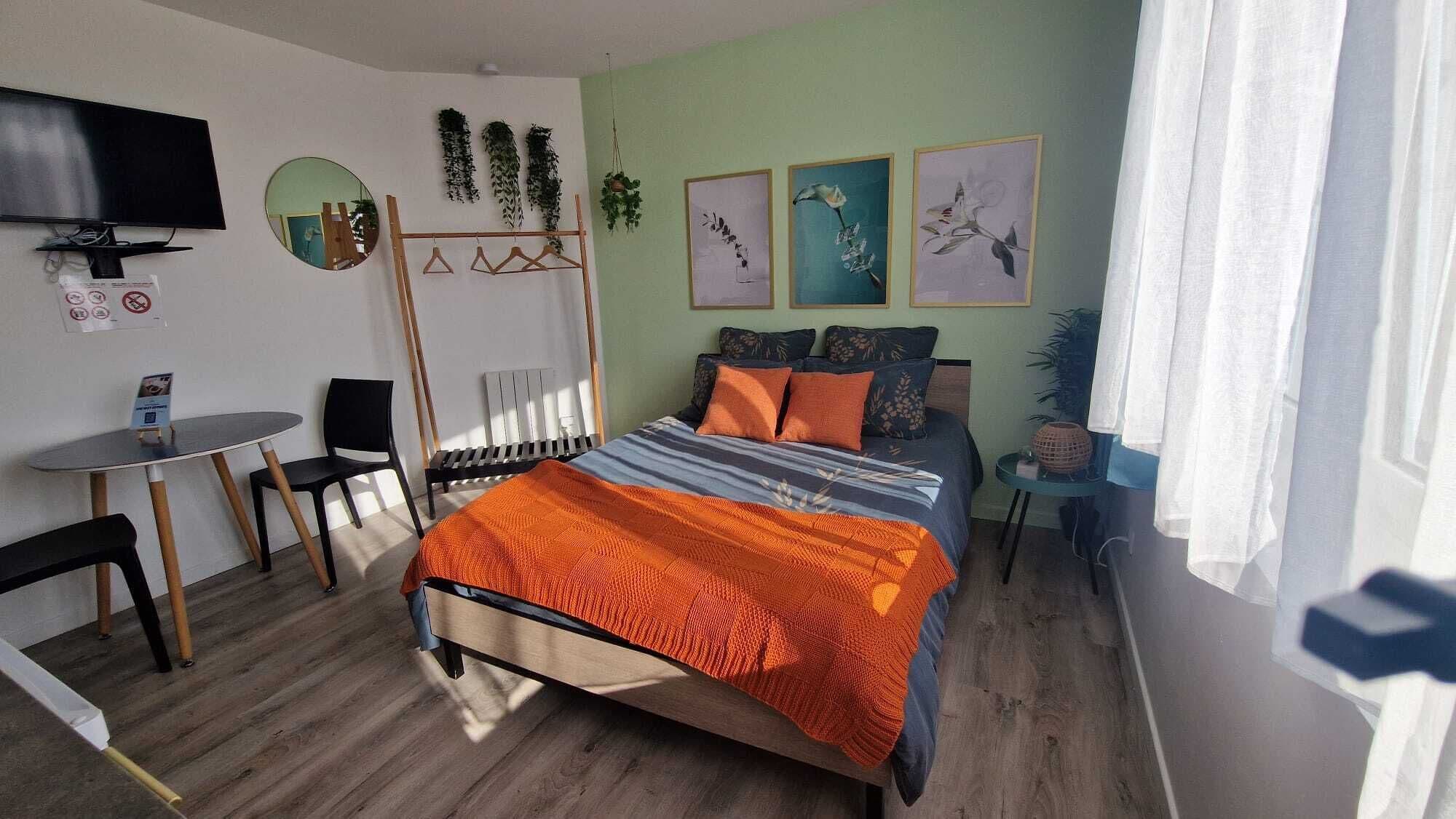 Une chambre à coucher comprenant un lit, un bureau, une chaise, un téléviseur et des œuvres d’art mural.