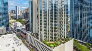 Un edificio alto con varios balcones y un jardín en la azotea.