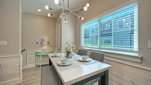 A dining area with a marble table, grey chairs, a teal side table, and a window with blinds. - Sleeps 33! 4 Condos, Walk to the Beach, Resort-Style Pool, Endless Summer Resort (Port Aransas)