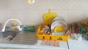 Een keuken met een spoelbak, een afdruiprek en diverse keukengerei.