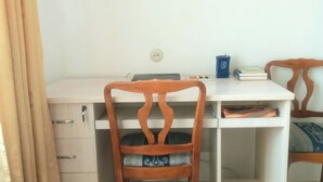 Een werkplek met een bureau, twee stoelen, een laptop en een blauwe mok.