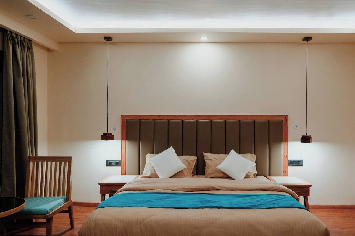 A bedroom with a large bed, two bedside tables, a wooden chair, and a TV.