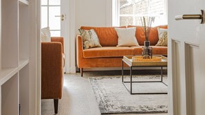 A living room with a sofa, a coffee table, and a bookshelf. - Skye Sands | Kinburn (No 2a) (St Andrews)