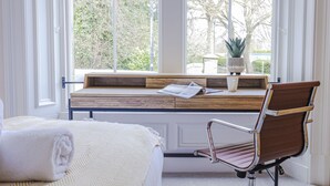 A bedroom with a large window, a wooden desk, a brown leather chair, and a bed with a white blanket. - Skye Sands | Kinburn (No 2a) (St Andrews)