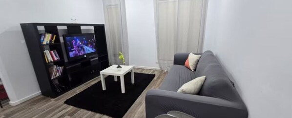 A living room with a black entertainment unit, a grey sofa, and a white coffee table. - Serenity Home 9 by Hiverooms (Pakenham)