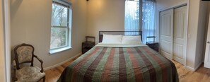 Een slaapkamer met een bed, een stoel, een nachtkastje en een raam.