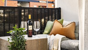 A seating area with a table, two wine glasses, a bottle of wine, and a potted plant. - The Vinyl Abode | Free Parking + 5-Minute CBD Walk (West Melbourne)