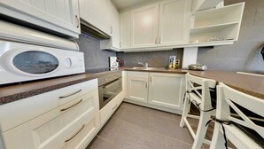 A modern kitchen with white cabinets, a microwave, an oven, and a sink. - Stay in Middelkerke with Sea View (MIDDELKERKE)