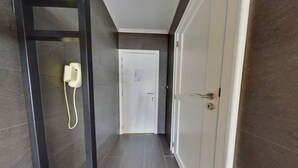 A narrow hallway with a door at the end, a phone on the left, and a door with a lock on the right. - Stay in Middelkerke with Sea View (MIDDELKERKE)