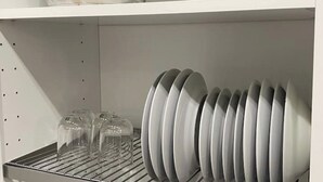 A kitchen with white shelves, a dish rack, and a few clear glass containers.