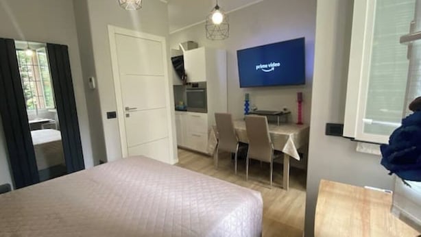 A modern bedroom with a bed, a desk, and a TV.