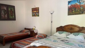 A room with two wooden beds, a standing lamp, and wall art.