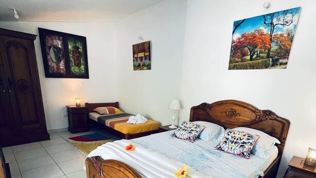 A bedroom with a wooden bed, a nightstand, a wardrobe, and a painting on the wall.