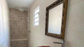 A bathroom with a skylight, a bathtub, and a shower area.
