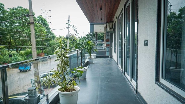 Un balcón cubierto con plantas en macetas, vista a la calle y un edificio con grandes ventanales.