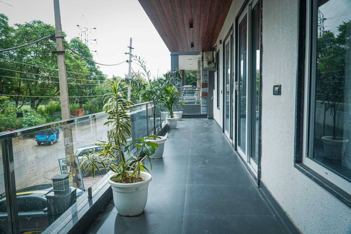 Un balcón cubierto con plantas en macetas, vista a la calle y un edificio con grandes ventanales.