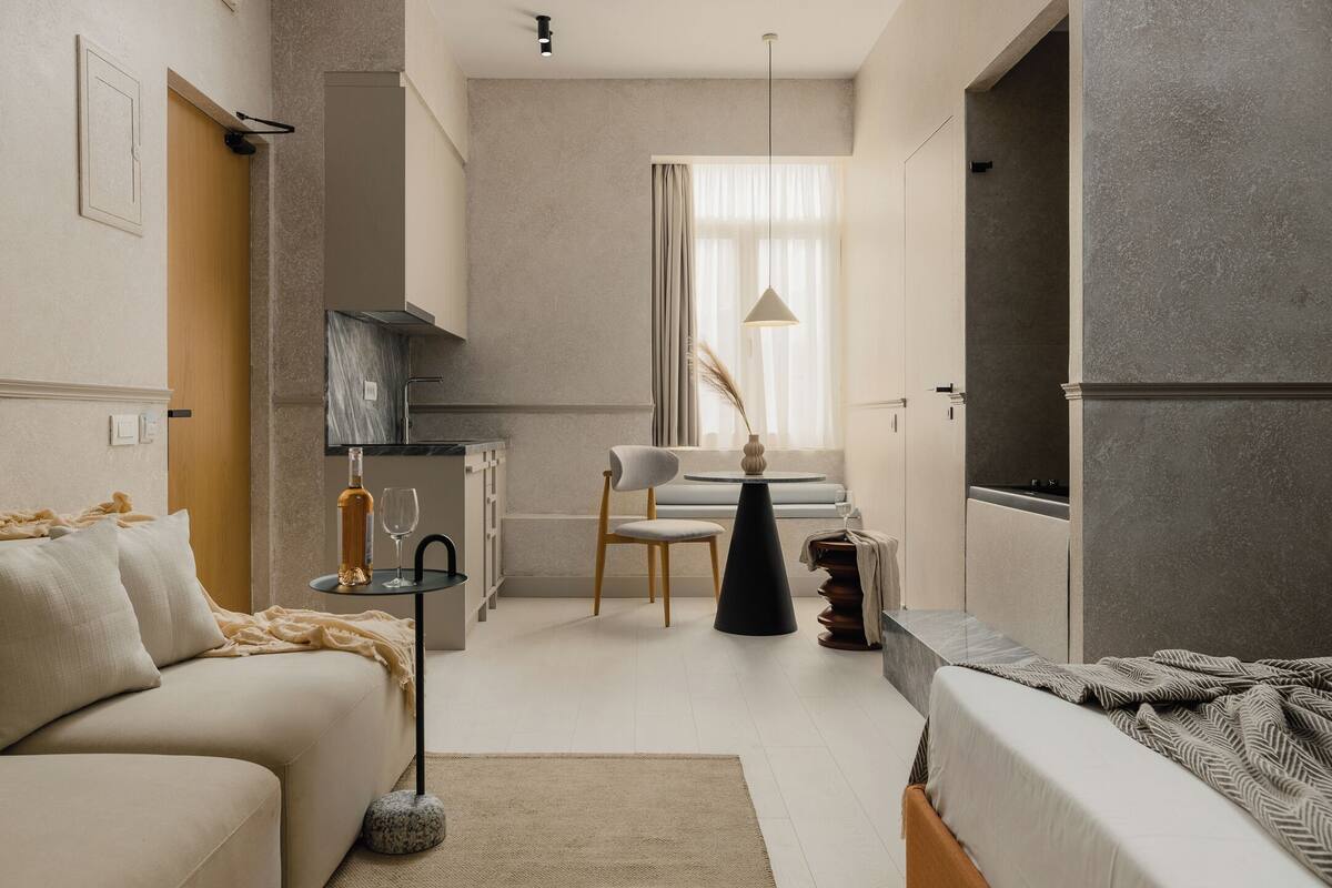 Une chambre d’hôtel moderne et minimaliste, dotée d’un canapé, d’une table à manger et d’un petit coin cuisine.