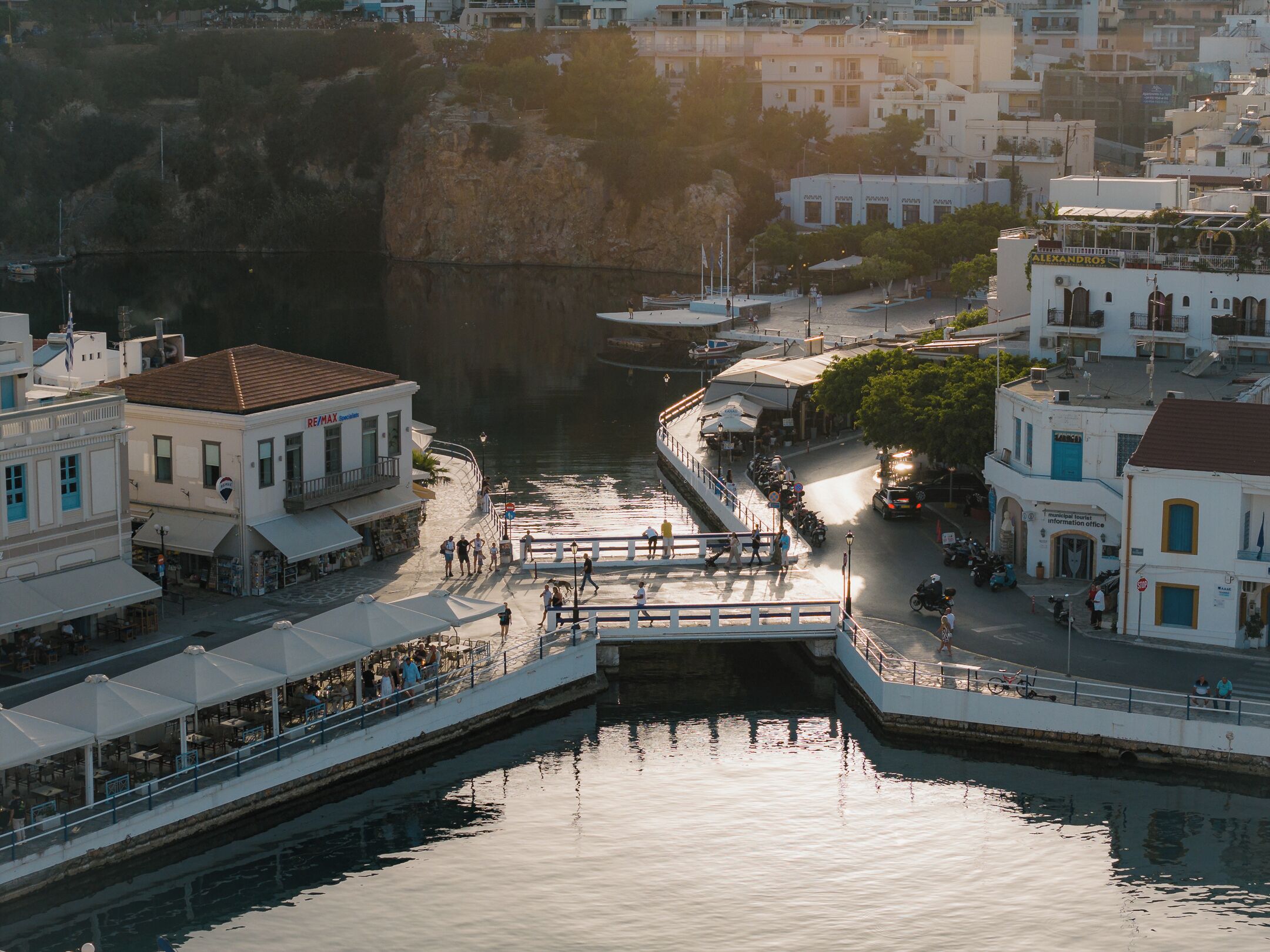 Un paseo marítimo con edificios, un puente y un puerto deportivo.