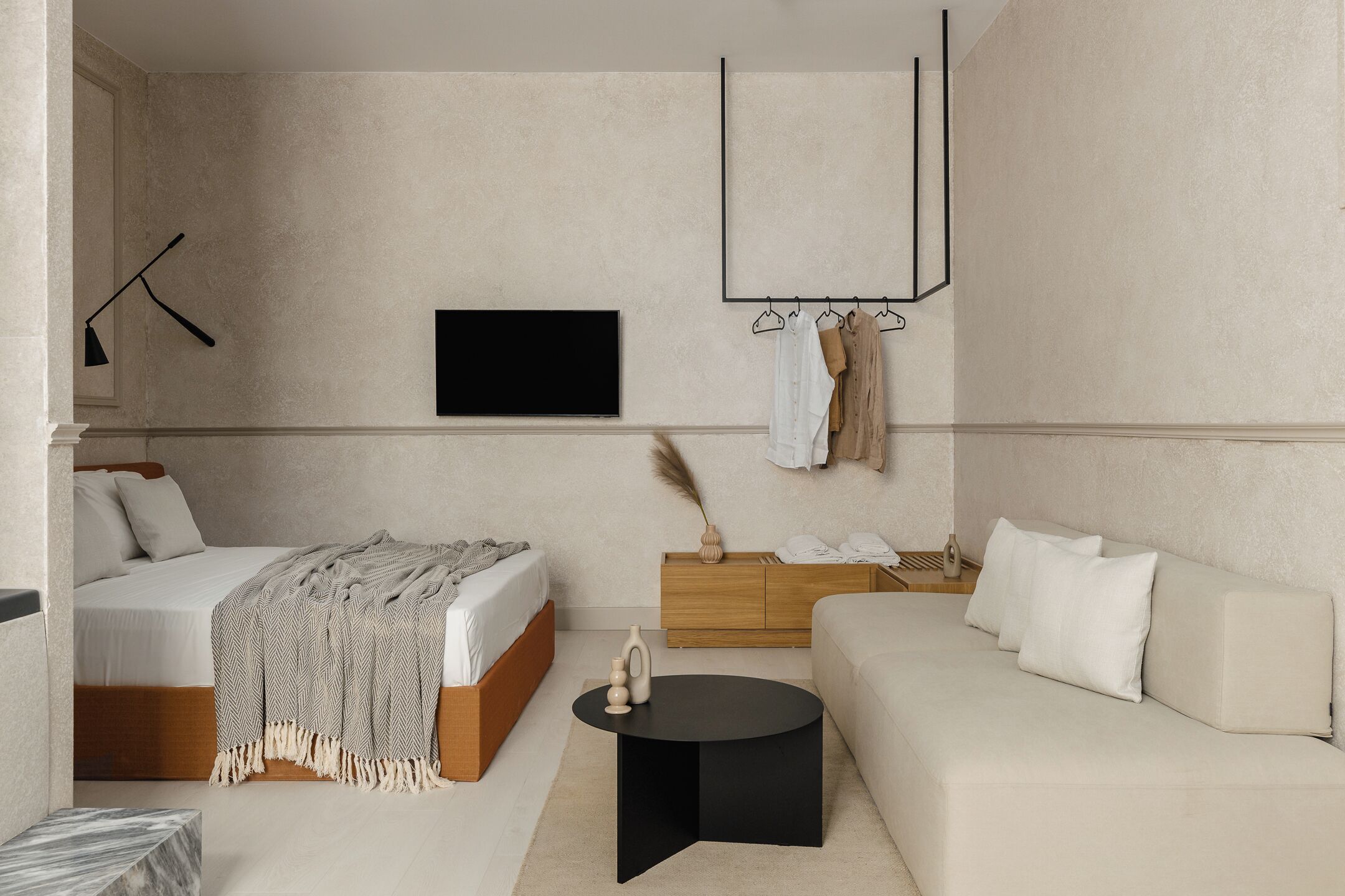 Ein modernes Schlafzimmer mit Bett, einer Couch, einem Fernseher, einem Kleiderschrank und einem Couchtisch.