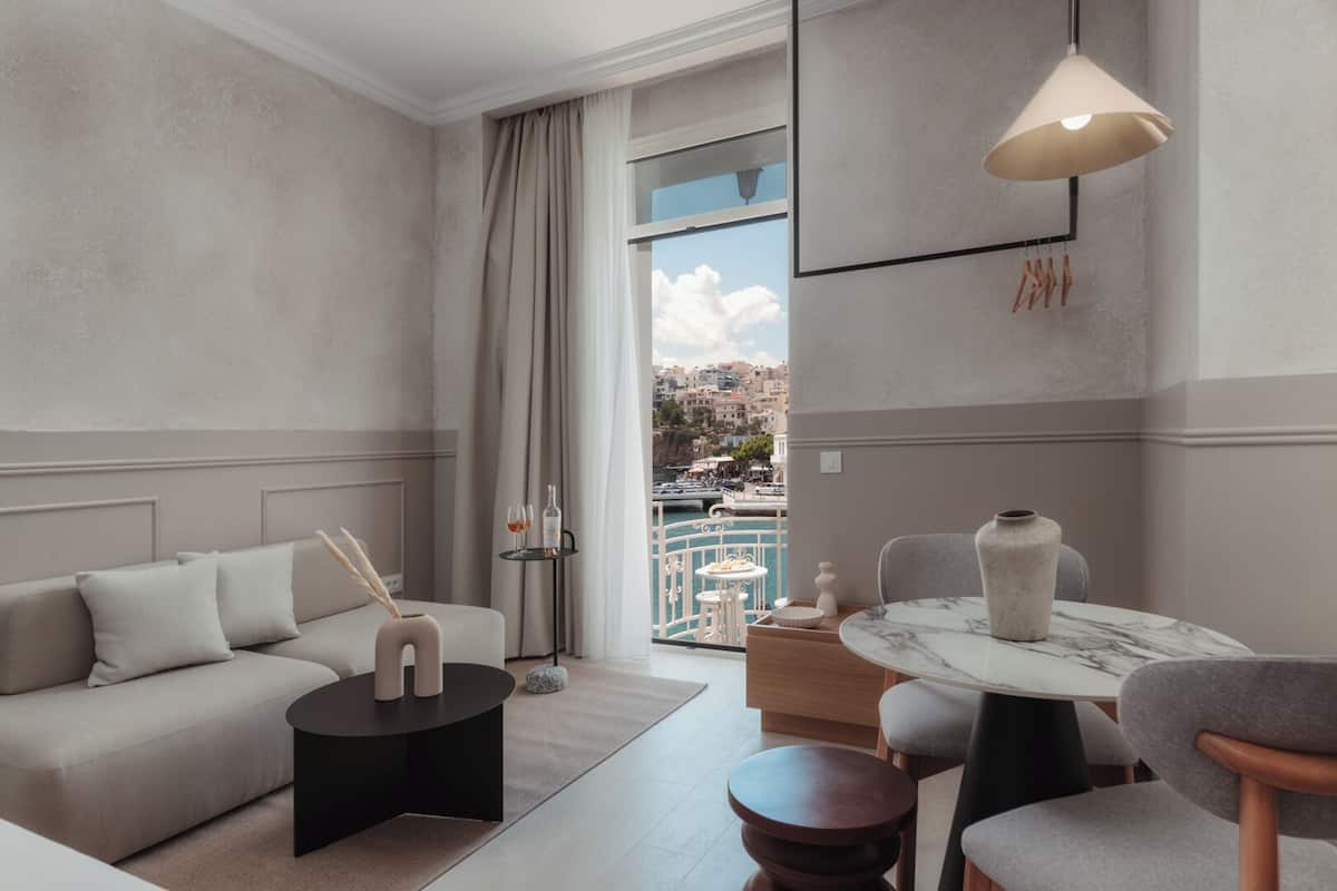 Un salon moderne avec un canapé, une table ronde et une vue sur un port de plaisance.