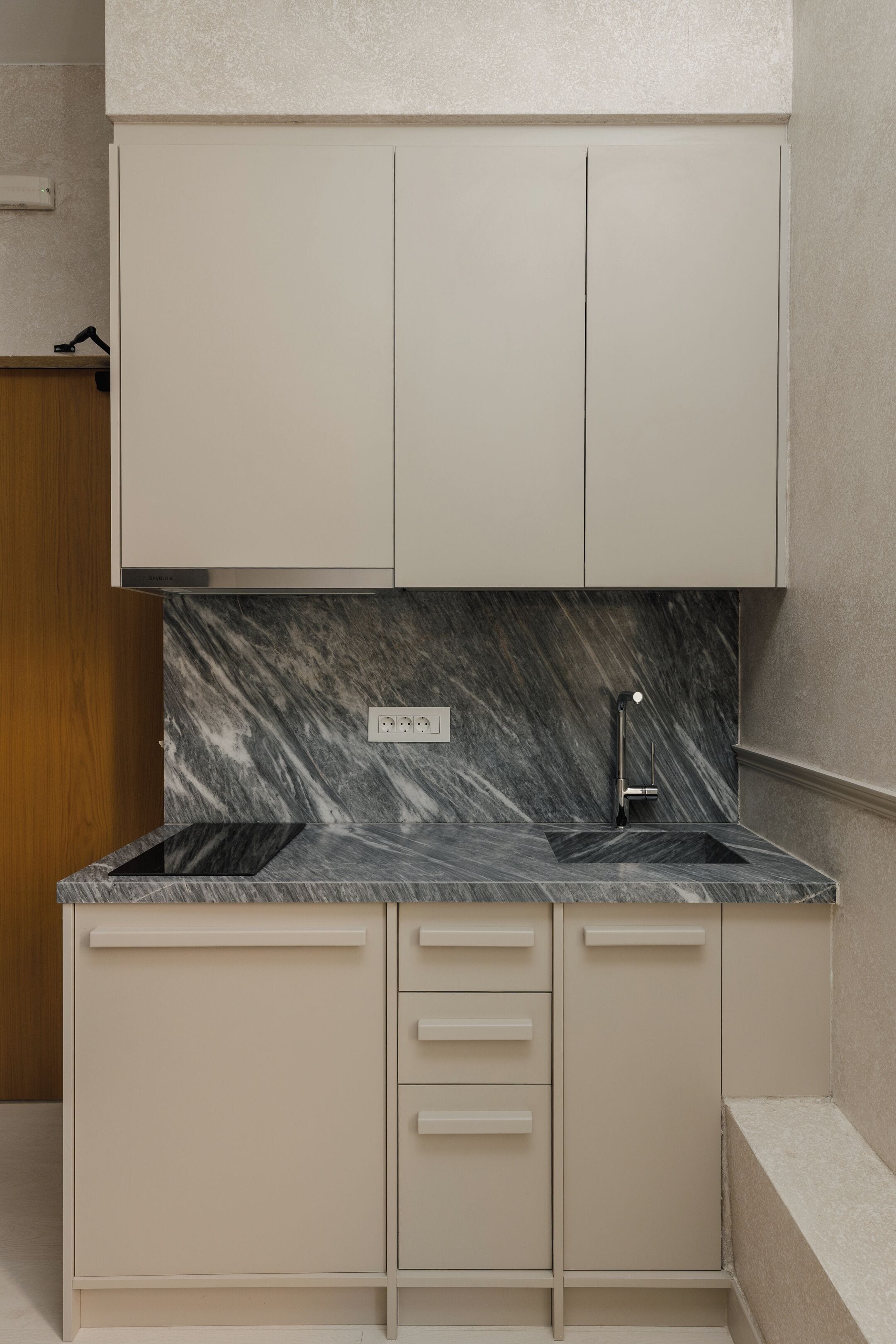 A modern kitchen with a marble countertop, two sinks, and a built-in oven.
