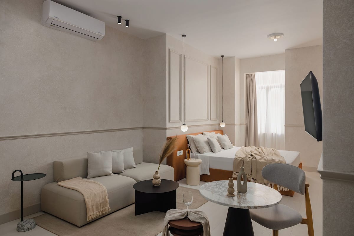 Une chambre d’hôtel moderne équipée d’un canapé, d’un lit, d’une télévision, d’une petite table et d’une chaise.