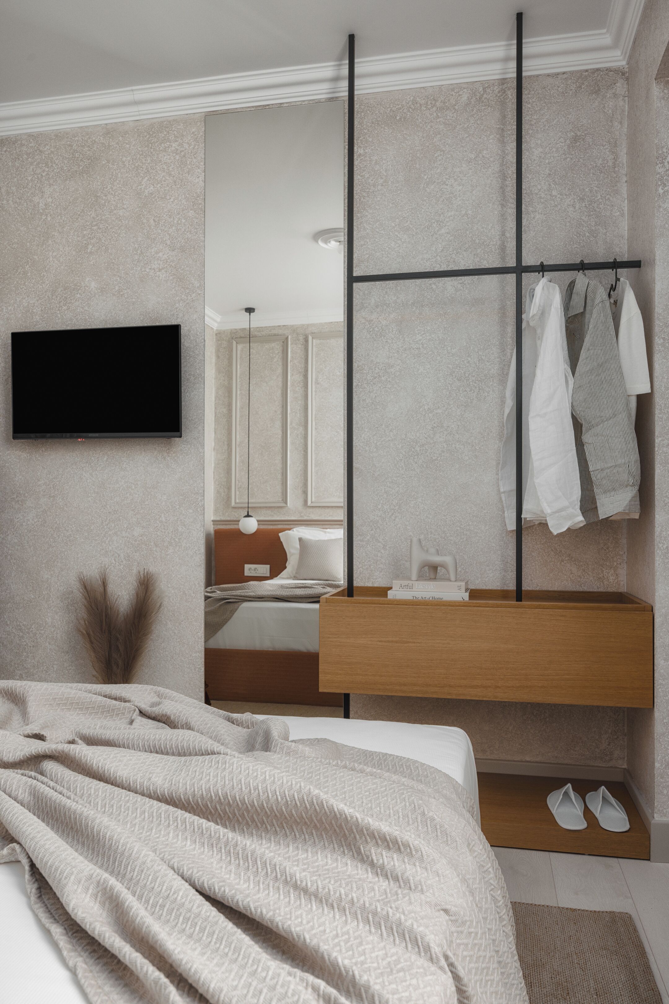 Een moderne slaapkamer met een bed, nachtkastje en een ingebouwde televisie.