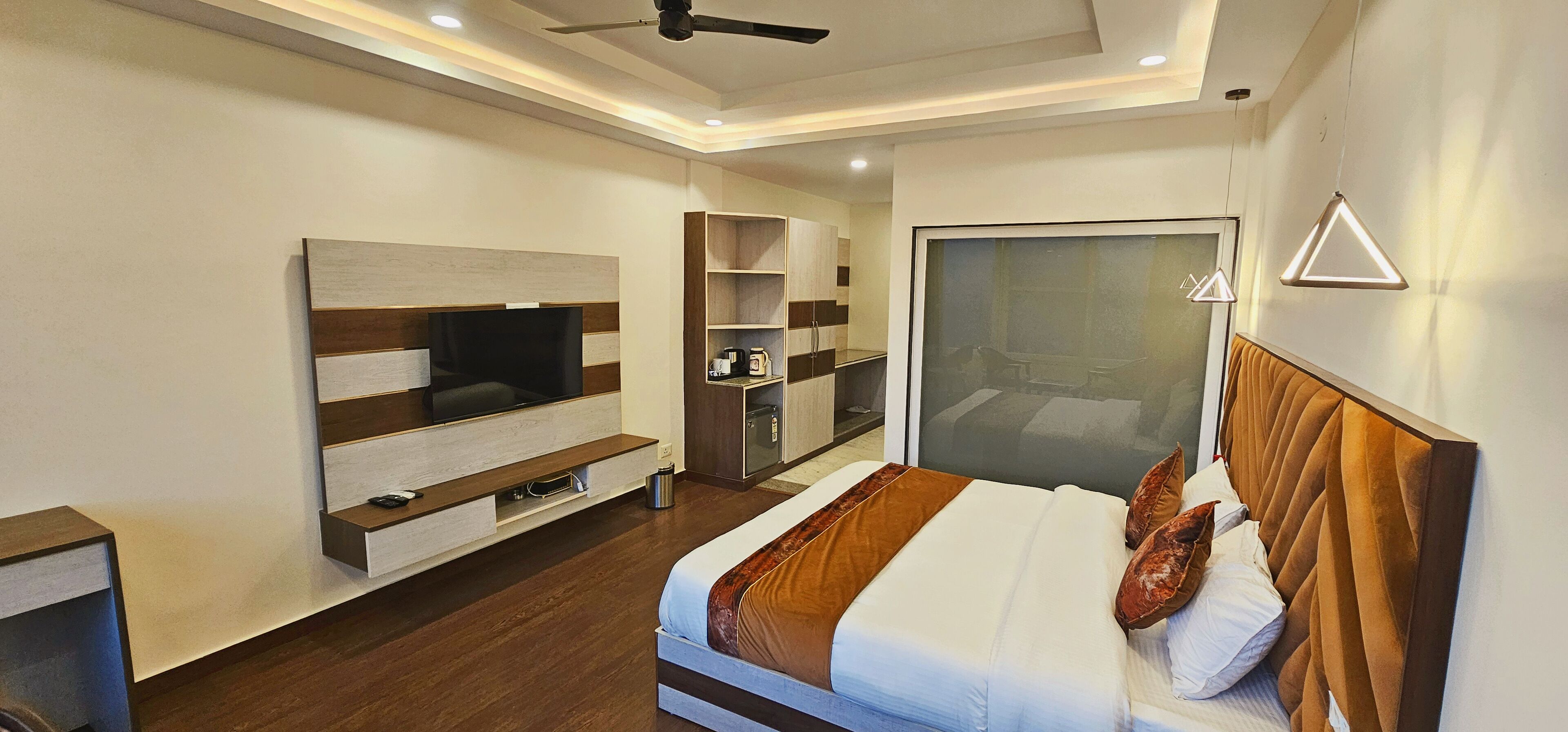 A modern hotel room with a large bed, built-in TV, and a minibar.