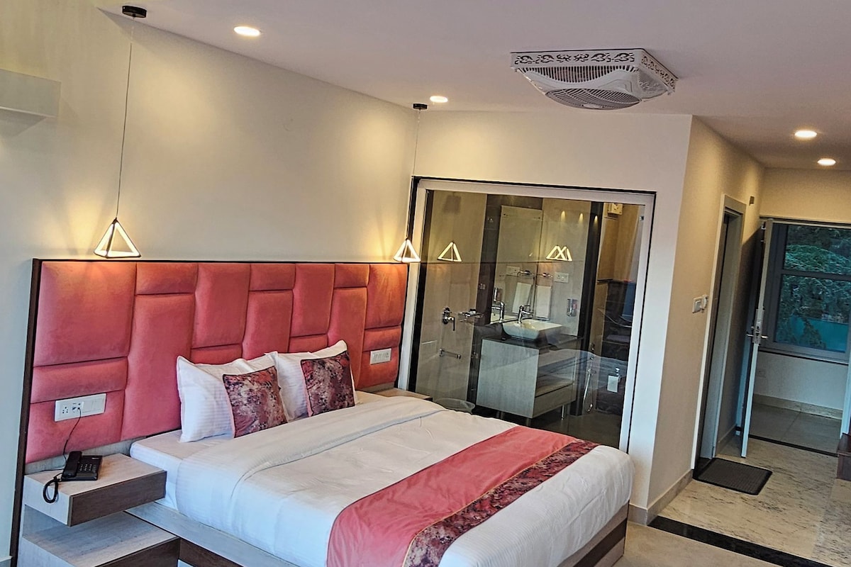 A modern bedroom with a large bed, a balcony, and a glass-enclosed bathroom.