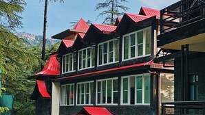 Un immeuble à plusieurs étages, doté d’une façade noire et de toits rouges, entouré de verdure.