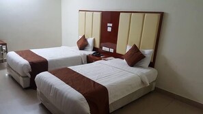 A hotel room with two single beds, each with a wooden headboard and white bedding.