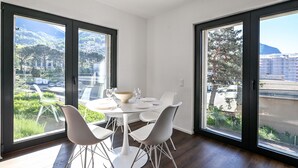 A dining area with a round table, white chairs, and a bowl.