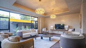 Una sala de estar moderna con sofá, sillones, una mesa de centro y un televisor.