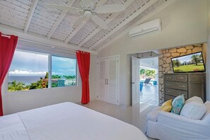 Una camera da letto con un letto, una TV, un armadio e vista sull'oceano.