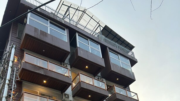 A multi-story building with balconies, large windows, and air conditioning units. - Udit Regency by west western kasol ( Central Heated and Air Cooled ) (Bhuntar)