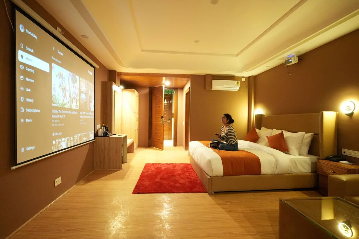Ein Hotelzimmer mit einem großen Bildschirm, der eine Speisekarte zeigt, einem Bett mit einer roten Teppich und einer Person, die auf dem Bett sitzt.