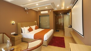 A modern hotel room with a large bed, bedside tables, a desk, and a projector. - Udit Regency by west western kasol ( Central Heated and Air Cooled ) (Bhuntar)