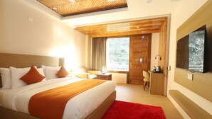 A modern hotel room with a large bed, a desk, a TV, and a view of the outdoors. - Udit Regency by west western kasol ( Central Heated and Air Cooled ) (Bhuntar)