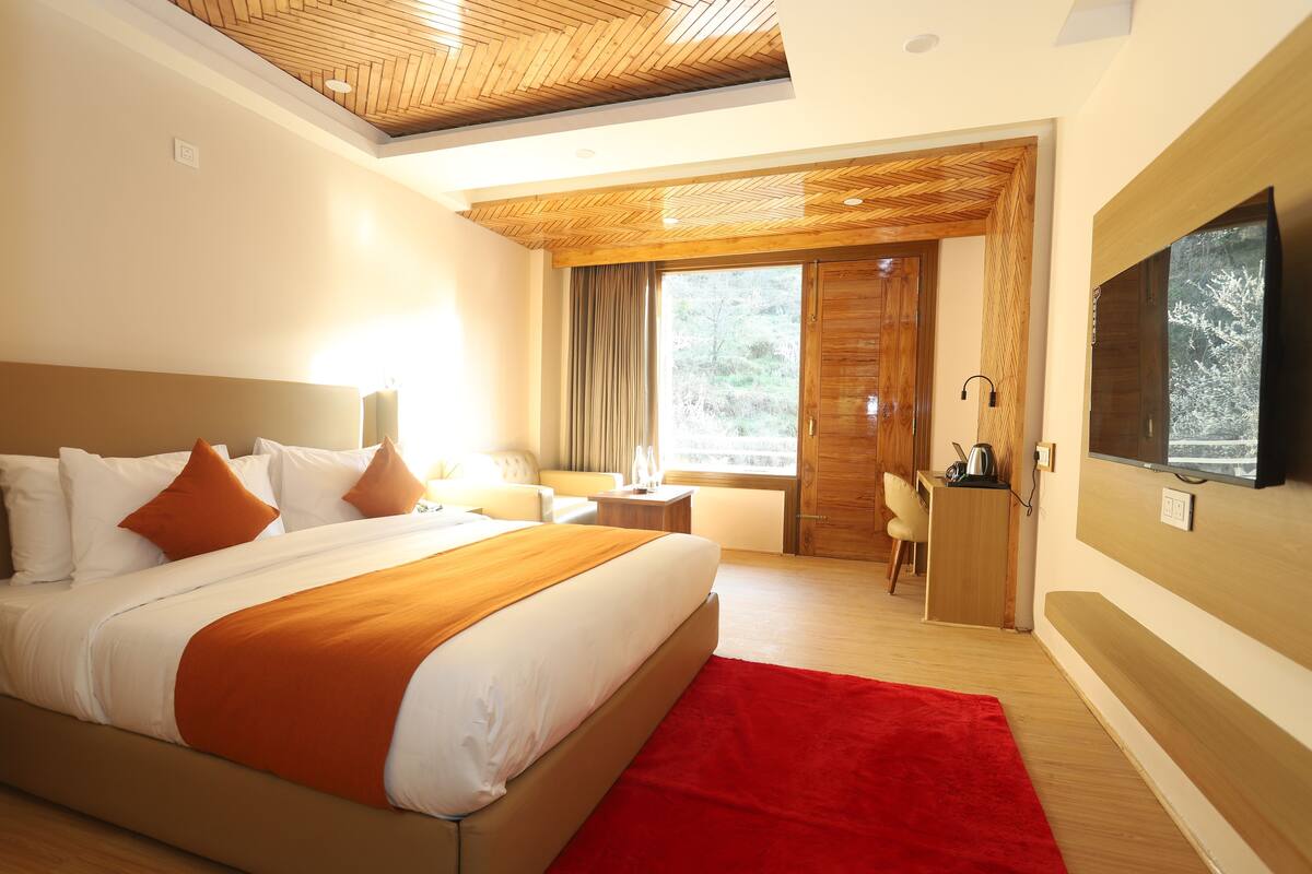 Ein modernes Hotelzimmer mit einem großen Bett, einem Schreibtisch, einem Fernseher und Blick ins Freie.