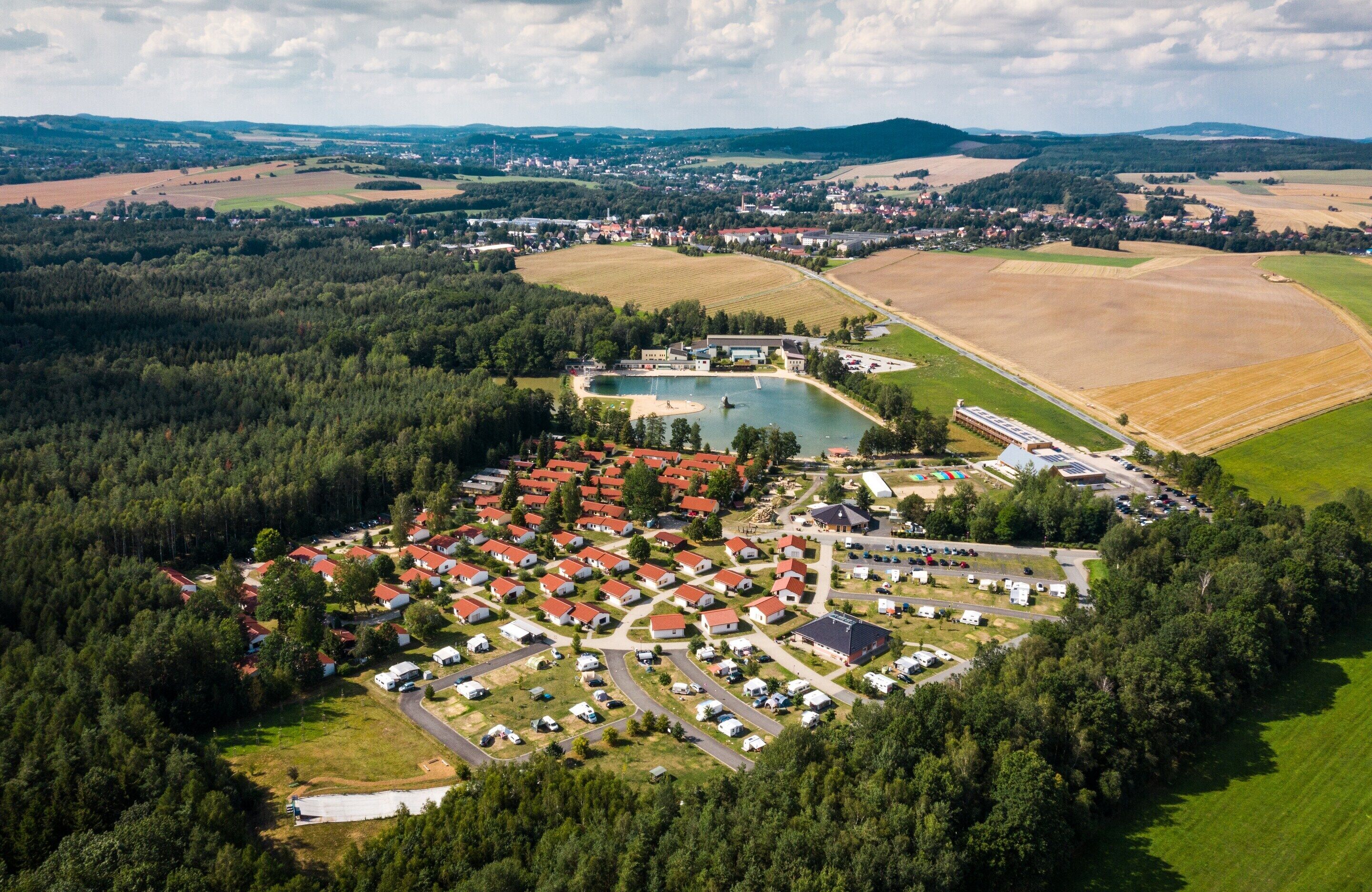 Vista aérea de una zona residencial con casas, un lago y campos circundantes.