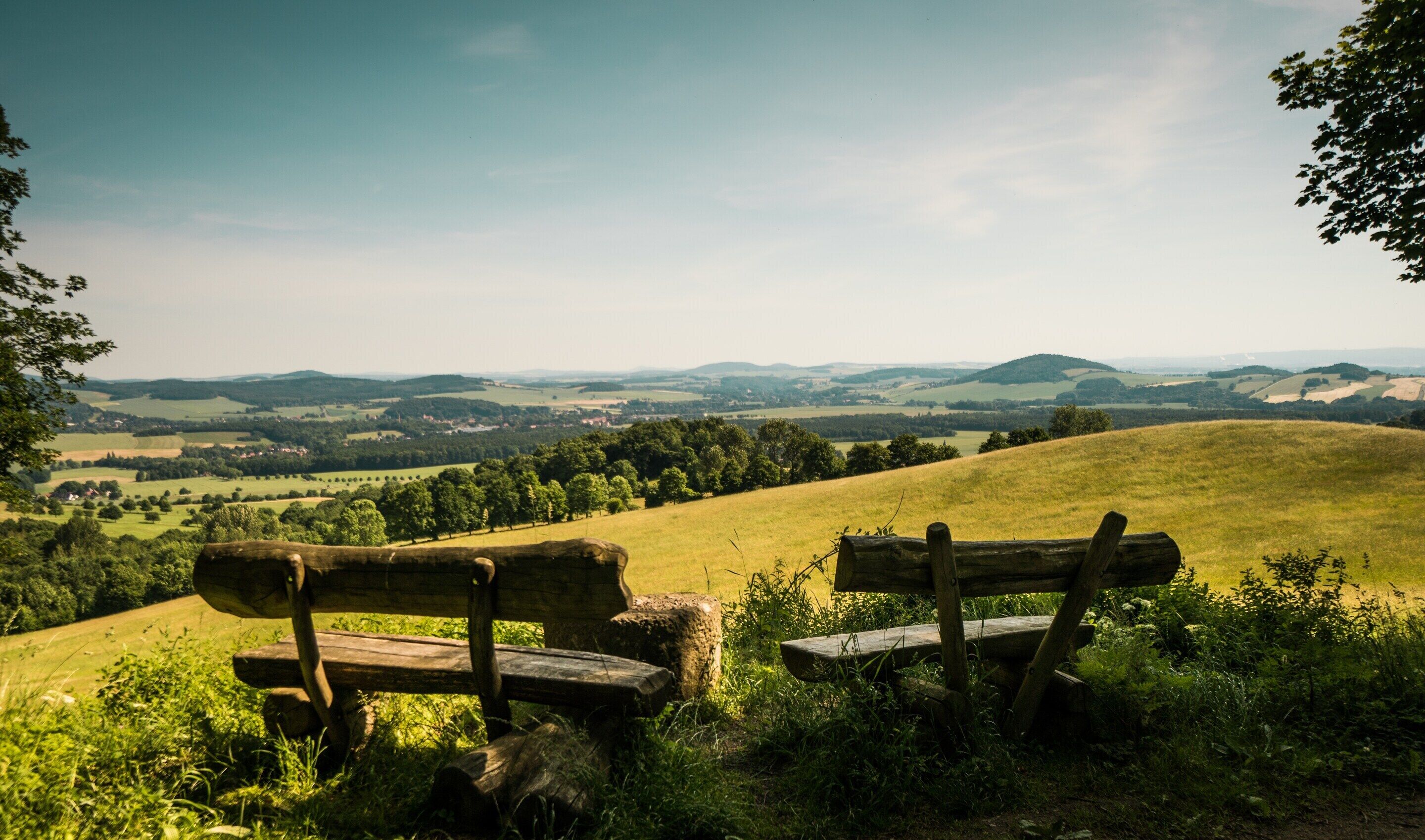 A bench overlooking a rural landscape with rolling hills and fields.