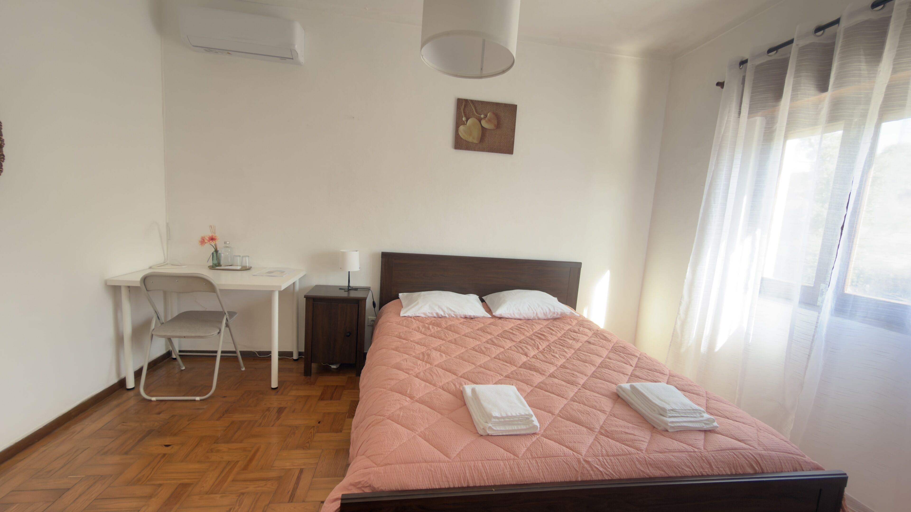 Quarto com cama, escrivaninha, cadeira e um pequeno armário.
