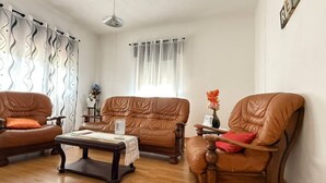 Una sala de estar con tres sillones de cuero, una mesa de centro de madera y una lámpara blanca.